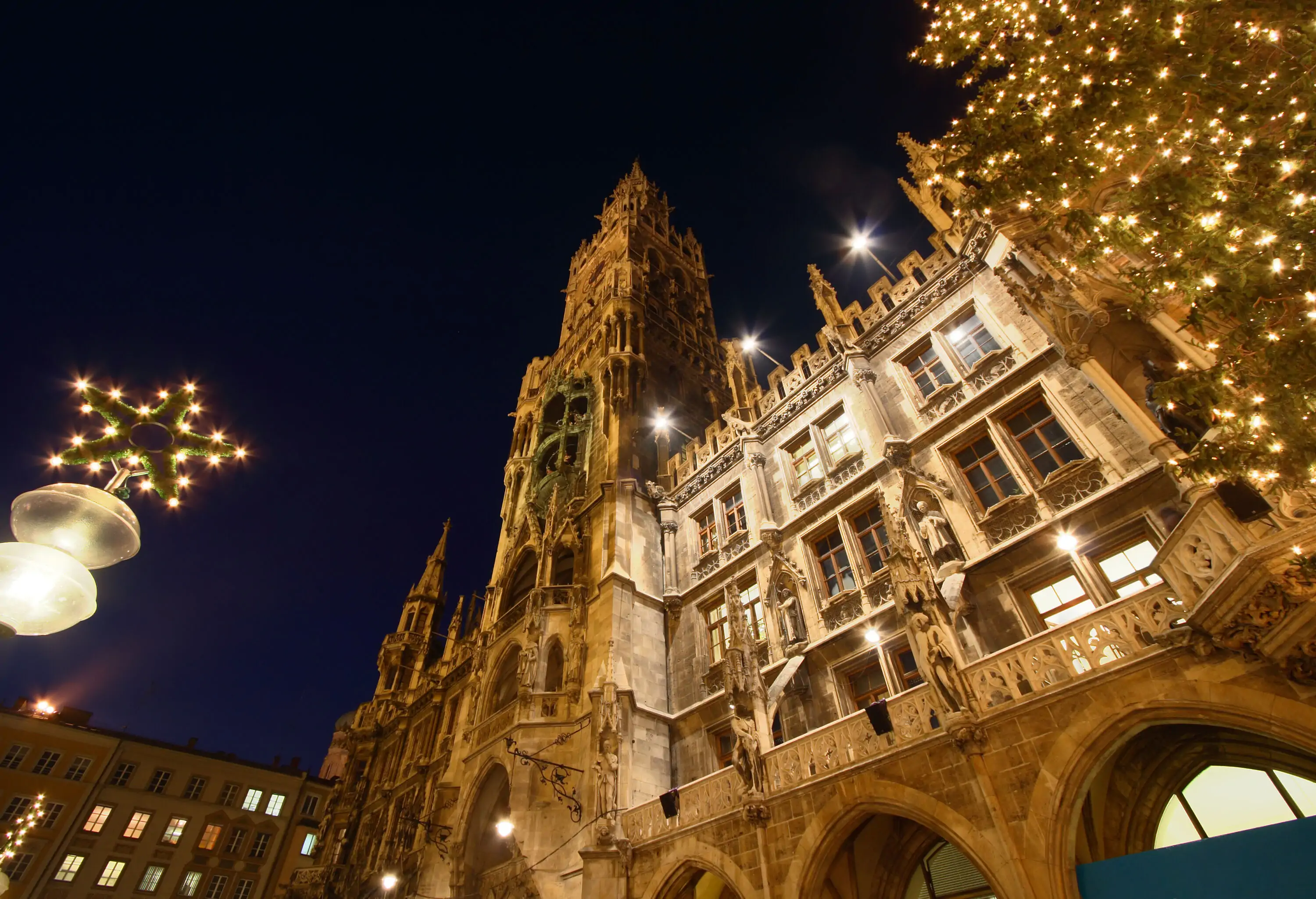 Façade of a Gothic style structure at night brightened by warm Christmas lights.