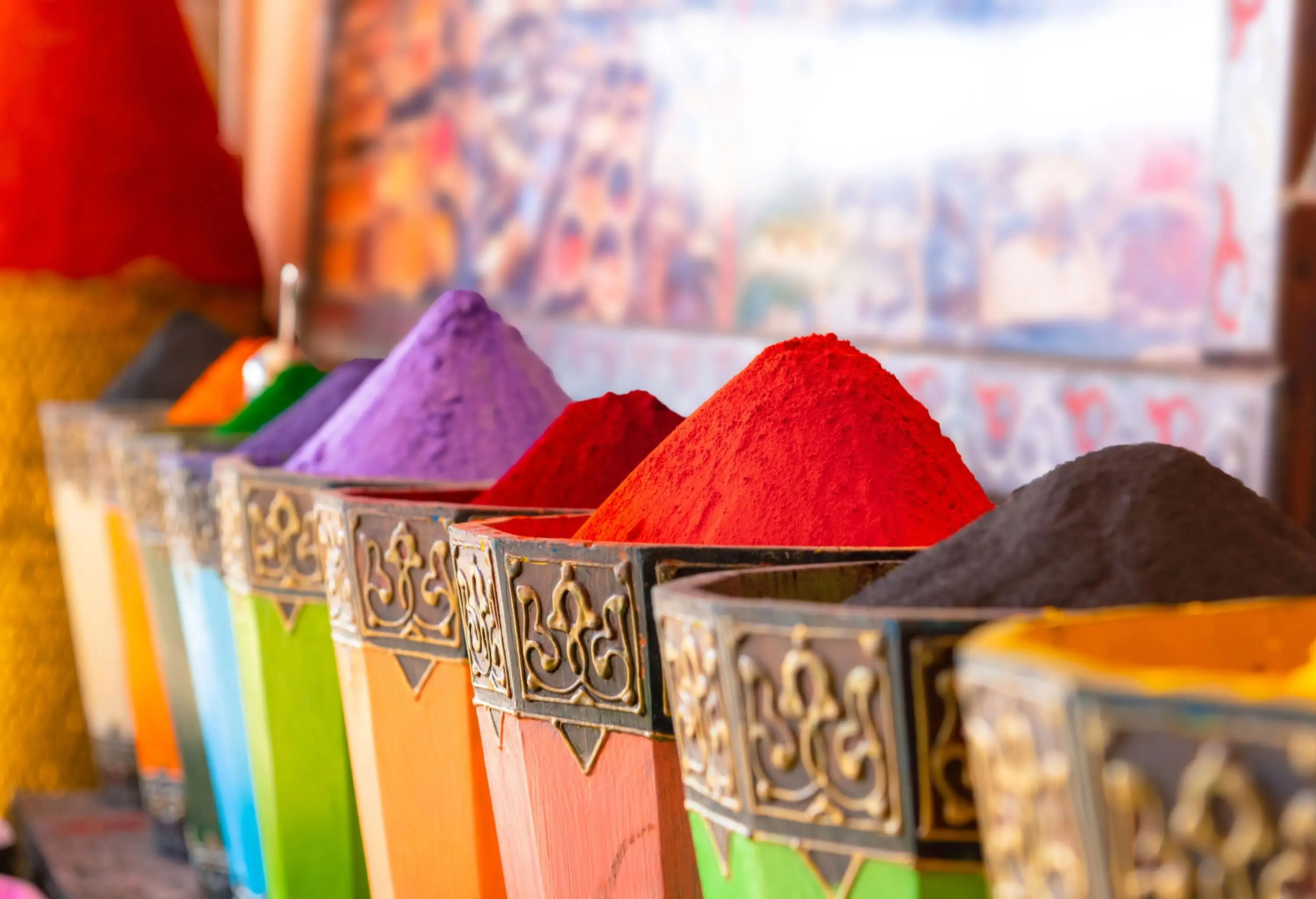 A row of colourful Moroccan powdered dye in colourful and ornated bins.